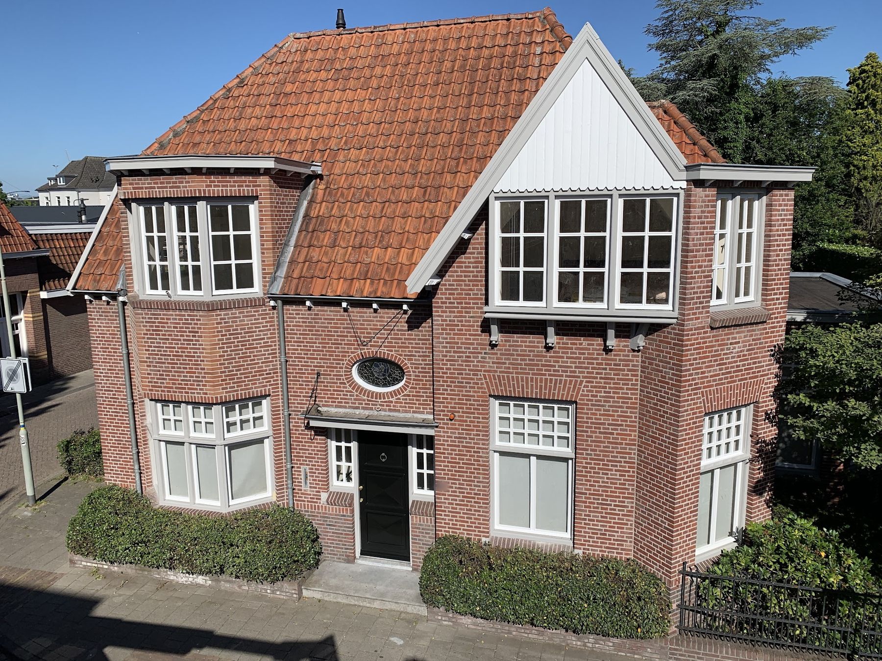 Karakteristiek rood bakstenen huis met lichtgrijze en witte kozijnen, erkers en een witte topgevel